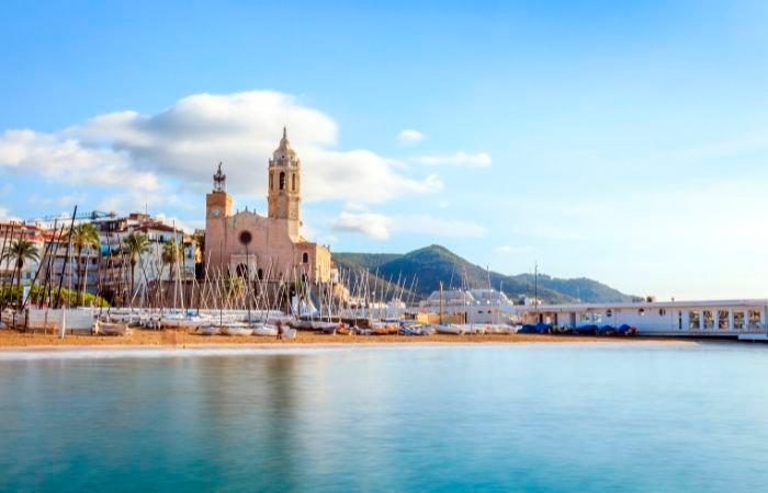 Strand von Sitges mit der Kirche im Hintergrund. Paddle Surf